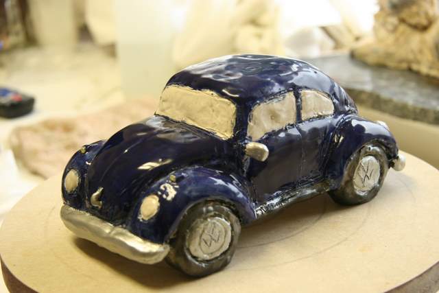 Volkswagen bug sculpture with blue glaze and chrome parts.
